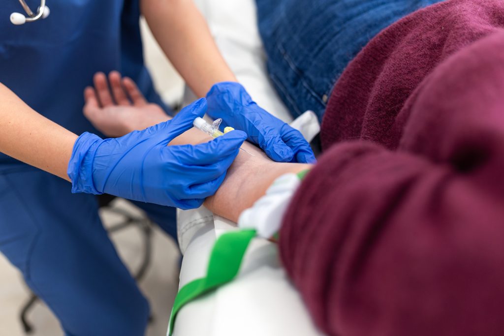 Clinician placing an intravenous line in a patient's arm before a nuclear stress test